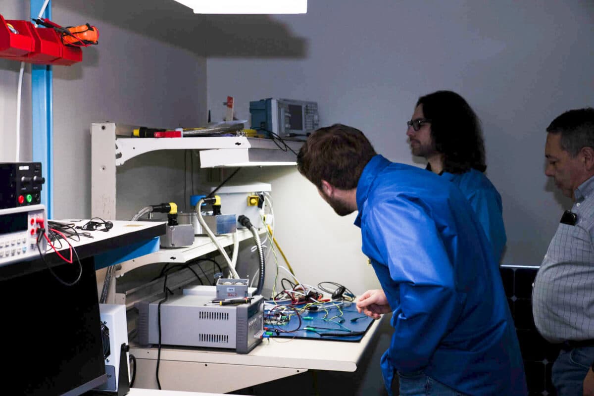 Signum team examining a circuit board at an electronics workbench